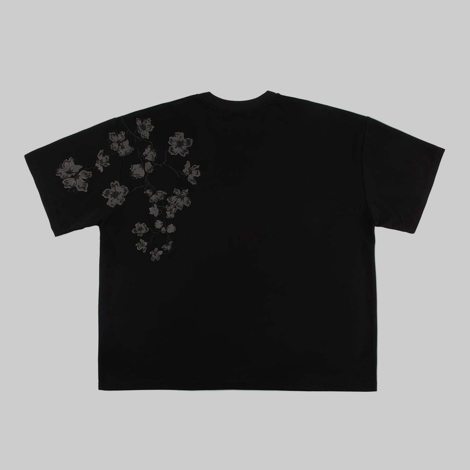 Black t-shirt with embroidered floral design on a white background