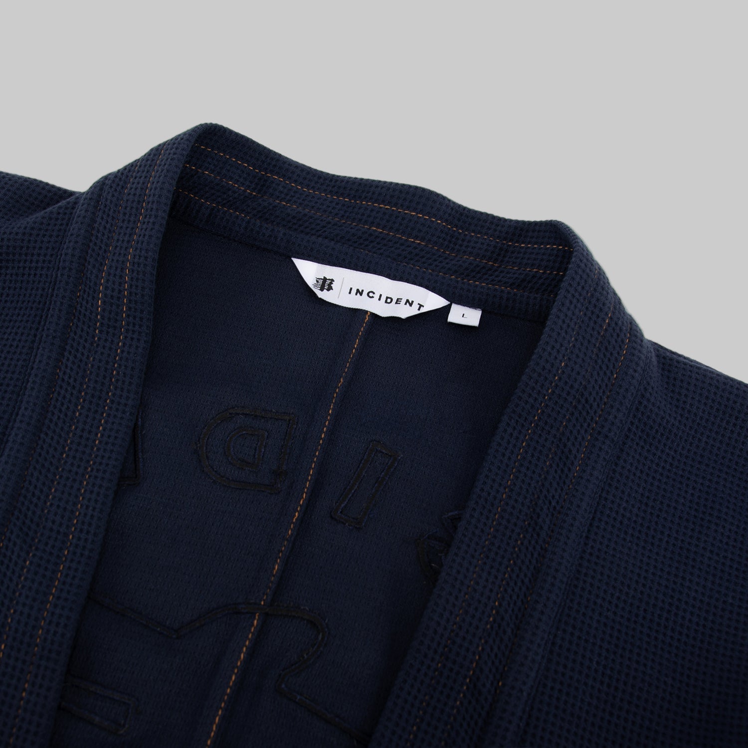 Navy blue martial arts gi with 'Incident' brand label on a white background