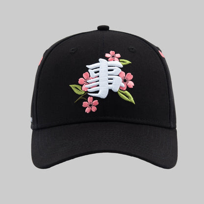Black cap with floral and white logo design on a white background