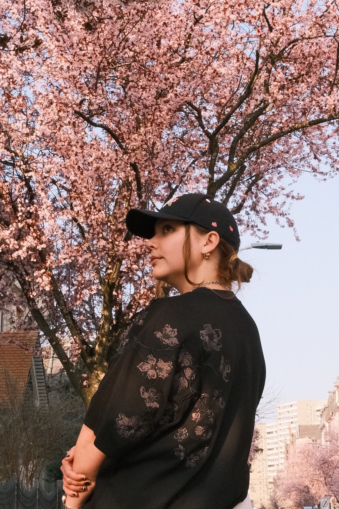 Person with a INCIDENT Cap and T-Shirt standing under a cherry blossom tree with a blurred background