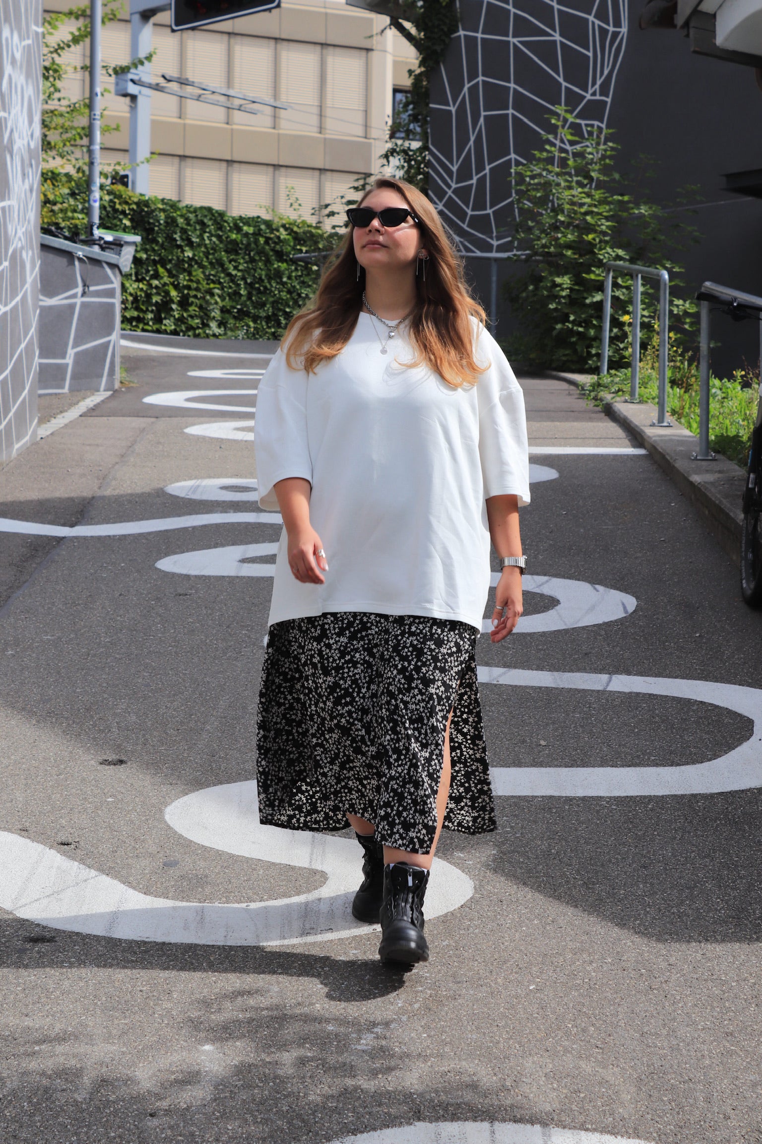 Woman in a white INCIDENT Pima Cotton T-Shirt and black patterned skirt walking on a street.